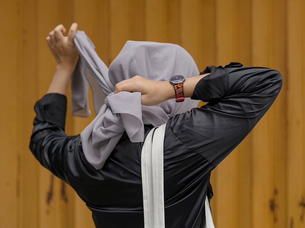 En kvinna knyter eller knyter upp en hijab.