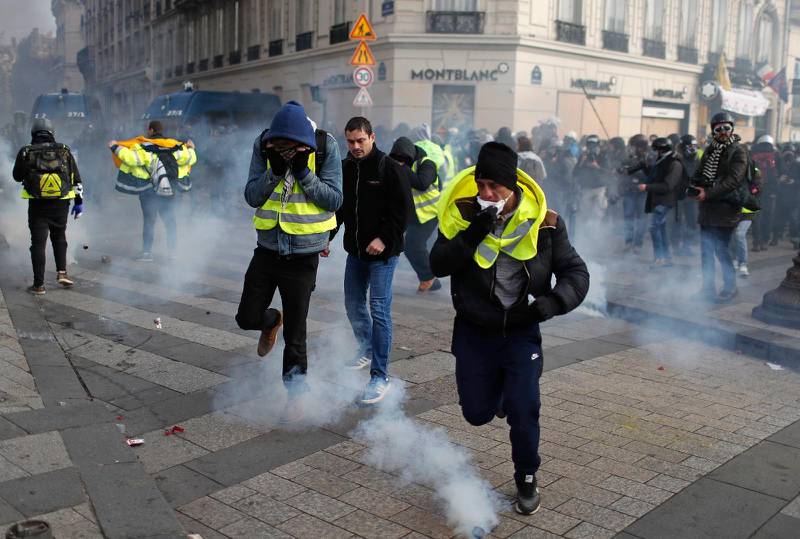 Demonstranter flyr undan polisens tårgas i Paris.